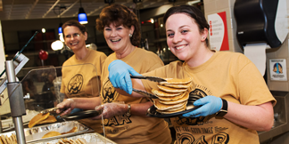 Employees serving students a midnight pancake breakfast.