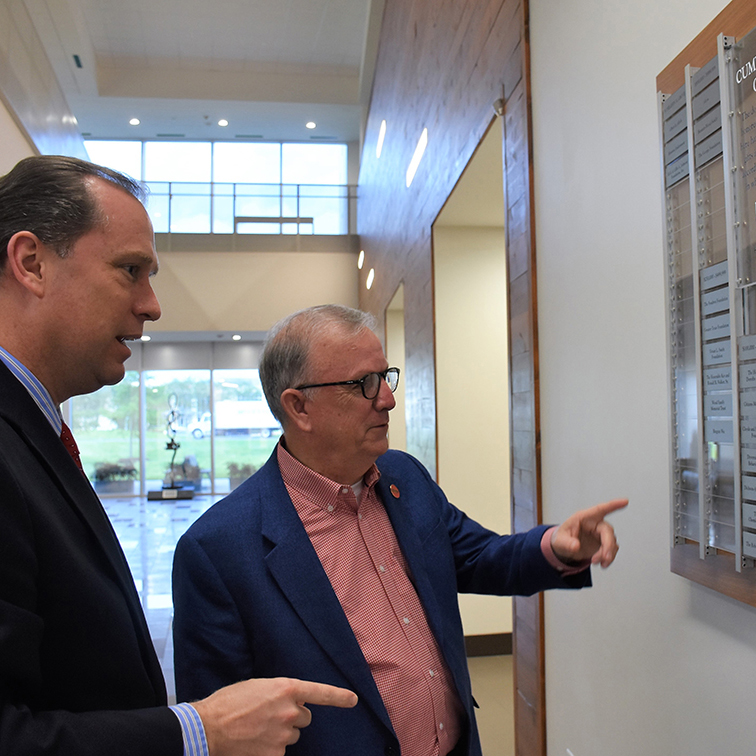 UHV President looking at the donor wall in University North